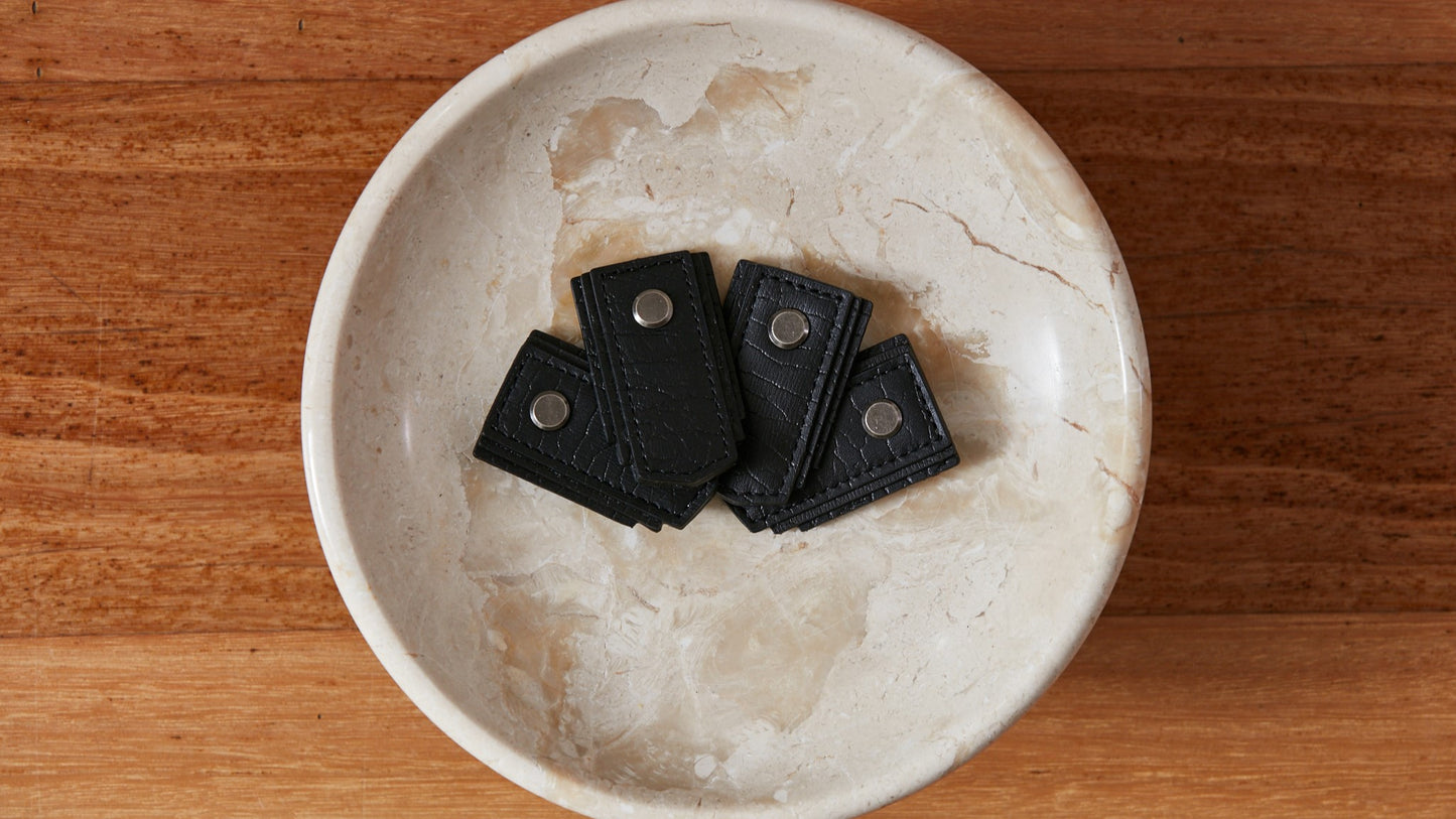 Black leather drawer pull handle by Sagitine with a sleek, modern design.